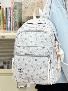 Close-up detail of grey school backpack with white star patterns and decorative charm.