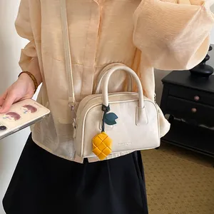 Detailed view of a cream leather pillow bag with a unique yellow charm accessory