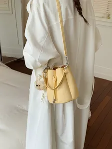 Fashionable yellow bucket crossbody bag for women with a cute bear plush charm accessory
