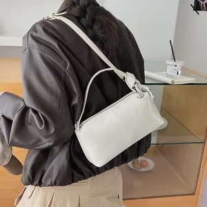 Detail of a white retro pillow bag crossbody worn with a stylish brown leather jacket