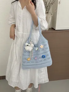 Detailansicht einer hellblauen Strick-Tragetasche mit bunten Blumen-Applikationen.
