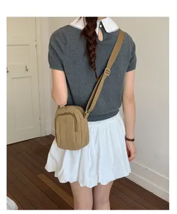 Detailansicht einer khakifarbenen Mini-Umhängetasche, getragen von einem Modell