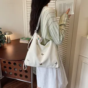 Close-up detail of large white bag with butterfly patterns being worn by a model indoors