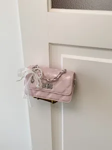 Elegant pink quilted small square crossbody bag featuring pearl and lace heart charms