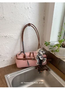 Detail view of a stylish pink Boston shoulder bag with brown straps and cute dachshund charm