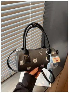 Detail of black cylinder handbag with cartoon cat prints and heart pendant charm