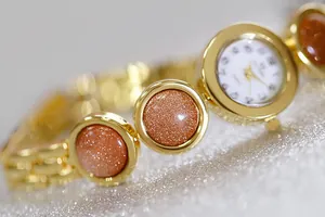 Primer plano de un reloj de pulsera dorado para mujer con piedras de arena brillantes
