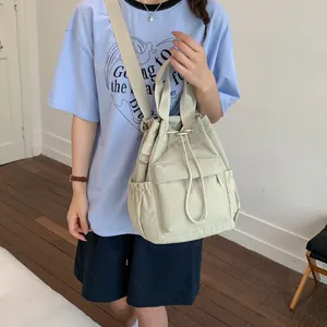 Mochila casual de nailon beige con cordón usada como bolso de hombro en escena