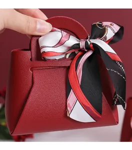 Gros plan d'un élégant sac à bonbons de mariage en cuir bordeaux avec foulard en soie
