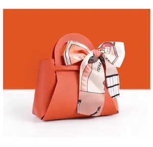 Gros plan d'un mini sac cadeau en similicuir orange avec un joli nœud en soie décoratif.