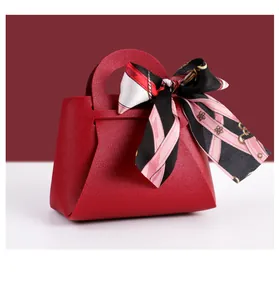 Détail d'un élégant sac cadeau en cuir rouge avec un foulard en soie à motifs attaché.