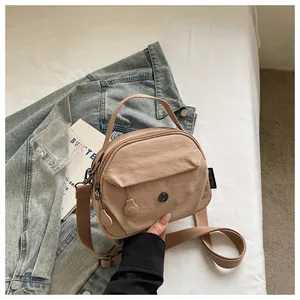 Detalle de un bolso bandolera casual de nailon caqui con bolsillos y correa tejida