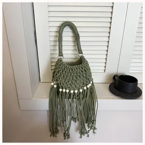 Detailed view of handmade green macrame bucket bag with long fringe tassels and white beads