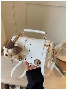 Close-up of a stylish retro white polka dot crossbody bag featuring a cute plush bear charm