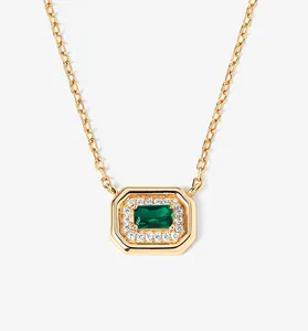 Detailed view of an emerald-cut green gem necklace with a sparkling halo in gold plating.
