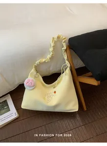 Bolso hobo amarillo con asa fruncida y bordado de fresa en una acogedora escena de interior.