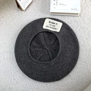 Close-up of a grey knitted beret with a white 'SEASON 13' patch on fluffy background