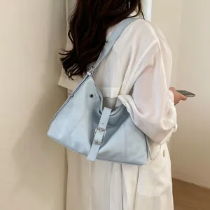 Detailed view of a stylish light blue hobo shoulder bag worn with a casual white coat.