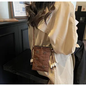 Close-up detail of retro brown velvet crossbody phone bag with beaded accents on model
