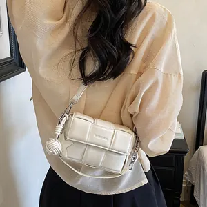 Cream woven crossbody bag detail on model showing the texture and rope knot charm