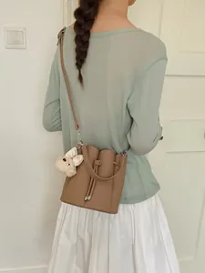 Fashionable tan leather bucket bag for women featuring a cute plush dog charm decoration