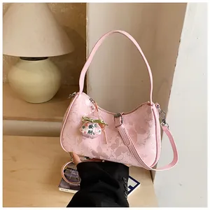 Detailed view of pink butterfly print underarm bag with decorative fortune charm