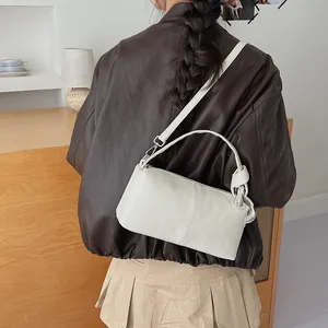 Minimalist white retro pillow shoulder bag shown on model wearing brown leather jacket