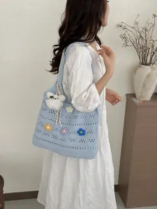 Lifestyle-Ansicht der hellblauen handgestrickten hohlen Einkaufstasche mit Häkelblumen