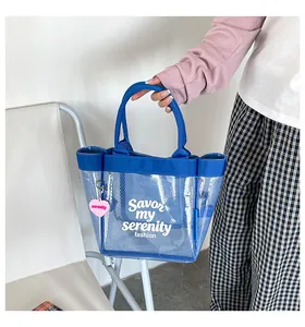 Detail view of blue transparent mesh tote bag with heart charm and slogan.