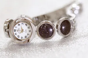 Primer plano de un reloj de cuarzo plateado para mujer con piedras de arena estelar