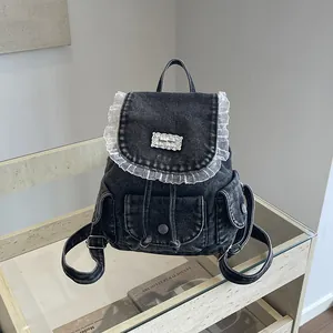 Zaino vintage in denim nero con volant in pizzo bianco su un ripiano in vetro minimalista