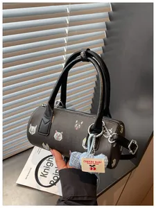 Detailed view of fashionable barrel bag with cute cat prints and a heart-shaped charm