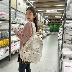 Asian girl wearing a white student backpack with multi-colored star patterns in store