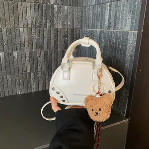 Detailed view of the white fashion bowling handbag featuring a cute teddy bear charm