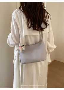 Detailed view of the lavender leather underarm bag with a white horse charm on a model.