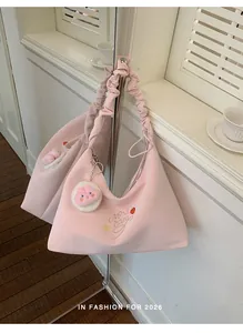 Vista detallada del bolso de hombro rosa plisado con un bonito peluche de fresa