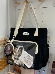 Black canvas tote bag with transparent display pocket and cute character accessories.