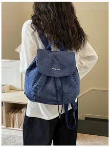 Detailed view of a navy blue checkered casual backpack for women worn by a female model