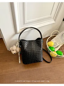 Detailed shot of a black woven bucket bag with a cute bear charm in a stylish vintage setting