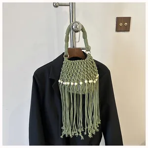 Detail view of a green macramé bucket bag featuring white beads and long fringe