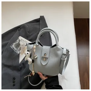 Détail d'un sac seau bleu clair avec breloque cheval dans un cadre lifestyle