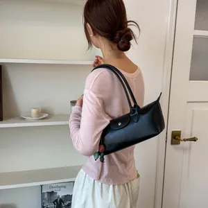 Élégant sac baguette noir porté par un mannequin dans un décor d'intérieur minimaliste