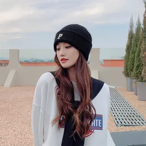 Close-up view of a stylish black knitted beanie featuring a white letter P embroidery