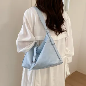 Back view detail of a light blue summer hobo bag styled with a white trench coat