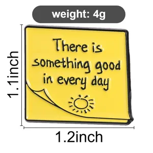 Detalle de pin de esmalte amarillo con frase inspiradora e información de peso de 4g