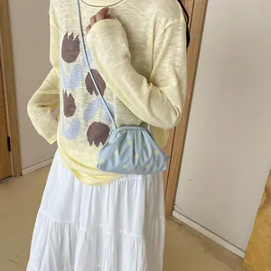 Light blue polka dot crossbody dumpling bag styled with a yellow knit sweater
