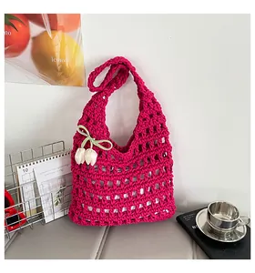 Detalle de un bolso de ganchillo magenta con diseño calado y un colgante de tulipán.