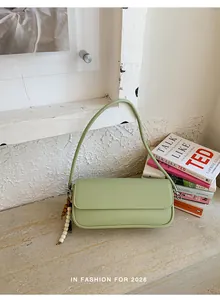 Close-up detail of light green baguette bag with beaded charm and lifestyle props