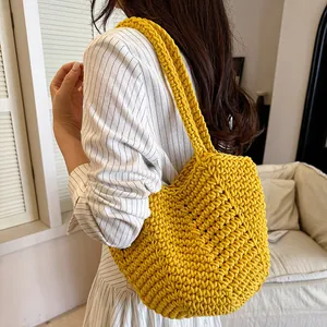 Detailed view of yellow hand-crocheted shoulder bag with soft knitted texture on model