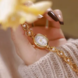 Dettaglio di un elegante orologio dorato da donna con cinturino in perle